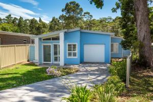 a blue house with a garage in a yard at Sanctuary Blue Pet Friendly 5 Mins to Hyams Beach in Sanctuary Point