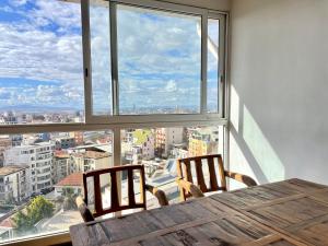 une table avec deux chaises devant une grande fenêtre dans l'établissement Hotel Le Pousse Pousse, à Antananarivo