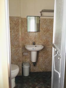 La salle de bains est pourvue d'un lavabo, de toilettes et d'un miroir. dans l'établissement Casa de Milagrosa inn, à Kalibo