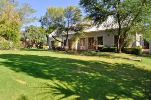 a house with a large yard with a large shadow at Thorntree Country Lodge in Oudtshoorn