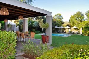 a patio with a table and chairs and a pool at Thorntree Country Lodge in Oudtshoorn