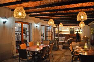 a dining room with tables and chairs and chandeliers at Thorntree Country Lodge in Oudtshoorn