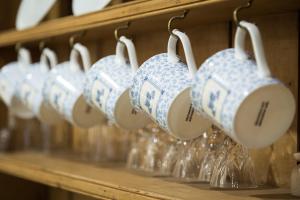 a row of coffee mugs hanging on a shelf at Coach House - detached cottage within 135 acres in Bromyard