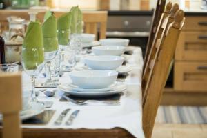 a long table with plates and bowls and wine glasses at Coach House - detached cottage within 135 acres in Bromyard