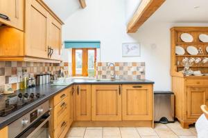 a kitchen with wooden cabinets and a stove top oven at Coach House - detached cottage within 135 acres in Bromyard