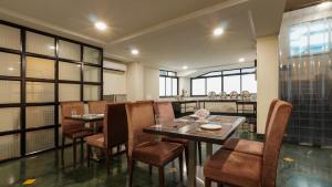 a dining room with tables and chairs and windows at Magnus Riverside Kalyani Nagar, Pune in Pune