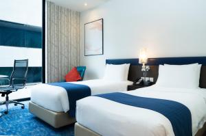 a hotel room with two beds and a chair at Holiday Inn Express Bangkok Siam, an IHG Hotel - SHA Extra Plus in Bangkok