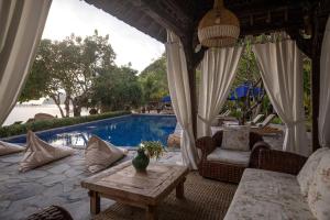 eine Terrasse mit einem Tisch und Stühlen neben einem Pool in der Unterkunft Plataran Komodo Resort & Spa - CHSE Certified in Labuan Bajo