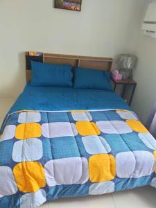 a bed with a blue and yellow quilt on it at YokosoCEBU & Private Parking in Cebu City