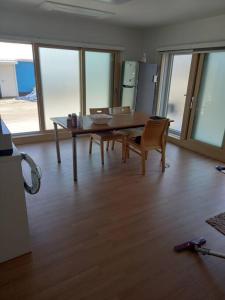 uma sala de jantar com mesa, cadeiras e janelas em Summer's House em Jeju