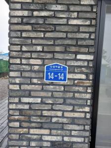 a brick wall with a blue sign on it at Summer's House in Jeju