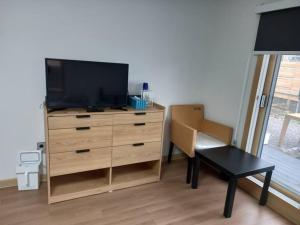un soggiorno con cassettiera, TV e tavolo di Summer's House a Jeju