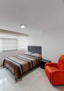 1 dormitorio con 1 cama y 1 silla roja en Puerto santa Ana 2 habitaciónes, en Guayaquil