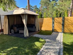 a gazebo with a couch under it in a yard at Jodłowy Zakątek NEW in Niechorze