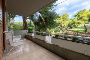 a balcony with two chairs and a view of trees at Phaedrus Living: Luxury Flat Vouliagmeni in Athens