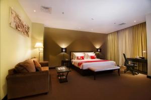 PRIME PARK Hotel Bandung في باندونغ: غرفه فندقيه بسرير واريكه