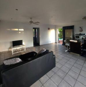 een woonkamer met een zwarte bank en een tafel bij Morningview Cottage - Self Catering Private Owned Rental in Durban