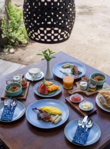 una mesa de madera con platos de comida. en Plataran Komodo Resort & Spa - CHSE Certified, en Labuan Bajo