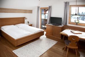 a bedroom with a bed and a desk and a television at Filzenhof in Kitzbühel