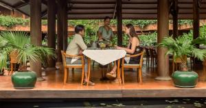 Un groupe de trois personnes assises à une table dans l'établissement Angkor Village Hotel, à Siem Reap