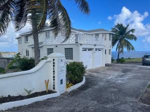 a white house with a fence and a palm tree at ‘MORIAH’ Private Room with Double Bed and shared bathroom in Saint Philip