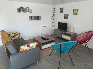 salon z kanapą, telewizorem i krzesłami w obiekcie Duplex 4/5 personnes sur cour w mieście Plouër-sur-Rance