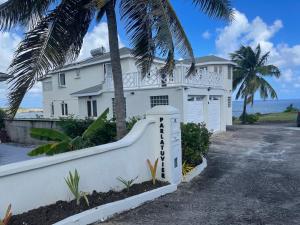 a white house with palm trees in front of the ocean at ‘MAYARO’ Private Room with Ocean View in Saint Philip