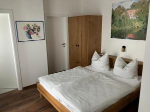 een slaapkamer met een bed met witte lakens en kussens bij Gasthaus Eggerberg in Neumarkt am Wallersee