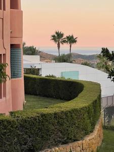 a green hedge in front of a building at Bonito apartamento con jardín privado in Finestrat