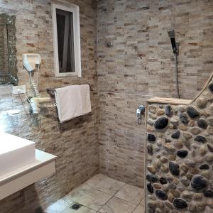 La salle de bains est pourvue d'une douche et d'un mur en pierre. dans l'établissement Green Monkey Resort Boracay, à Boracay