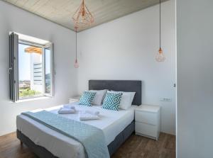 a white bedroom with a large bed with blue pillows at Lectus Mykonos in Paraga