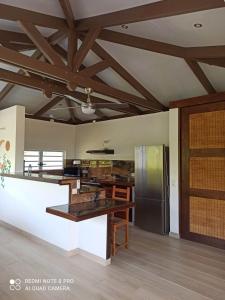 a large kitchen with wooden ceilings and a refrigerator at La Maison Du Voyage in Tevaitoa