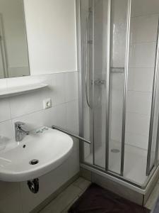 biała łazienka z prysznicem i umywalką w obiekcie Gasthaus Eggerberg w mieście Neumarkt am Wallersee