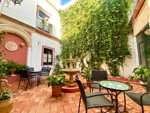 een patio met tafels en stoelen en een fontein bij El Rincón de las Descalzas in Carmona