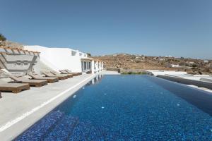 a swimming pool with blue water next to white buildings at Lectus Mykonos in Paraga