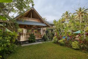a house with a porch and a yard at Gynandha Ubud Cottage in Ubud