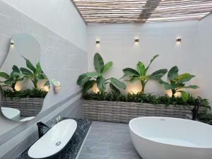 baño con bañera y 2 lavabos y plantas en Sea House Hotels and Apartments, en Vung Tau