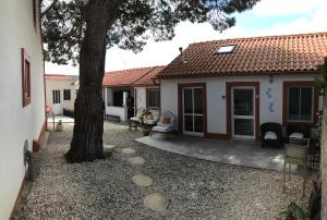 un patio trasero con un árbol y sillas y una casa en Casa o Futuro, en Alcobaça