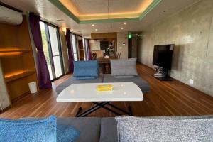a living room with a couch and a table at Mon Refuge Prive 屋上露天風呂のある隠れ家 in Motobu