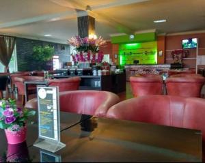 a restaurant with red leather chairs and a bar at THE IGNISLO HOTEL SORONG in Sorong