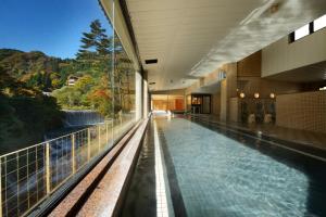 a swimming pool in a building with a view of a waterfall at Sansuiso Tsuchiyu Spa in Fukushima