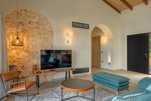 een woonkamer met een tv en een tafel en stoelen bij Ktima Agrapidos - Grandpa Villa in Póros