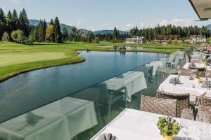a view of a golf course with tables and a lake at APART Resort Westendorf in Westendorf