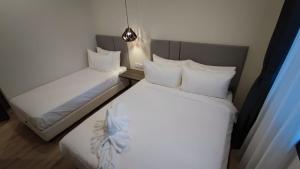 two beds in a room with white sheets and pillows at De Luna Hotel Sri Petaling in Kuala Lumpur