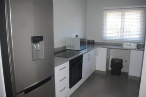 una cocina con armarios blancos y un aparato negro en Barefoot Bungalo, en Amanzimtoti