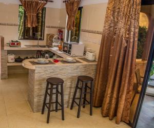 a kitchen with two bar stools at a kitchen counter at Les Elles Guesthouse Self Catering in Baie Lazare Mahé