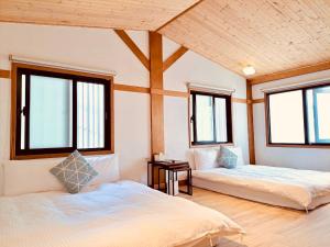 dwa łóżka w pokoju z oknami w obiekcie 末廣通二館 日式包棟民宿Suehirodori Japanese Entire Homes No2 w mieście Tainan