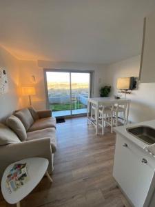een keuken en een woonkamer met een bank en een tafel bij Vue sur dunes ! in Sangatte