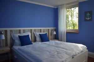 a blue bedroom with a large bed with blue walls at Liebevoll hinterm Deich - Ferienwohnungen in Lehe