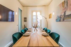una mesa larga en una habitación con sillas verdes en Rovelli 41 by Rent All Como, en Como